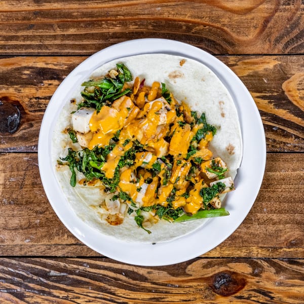 DGT Tacos Fort Collins' chicken taco with green vegetables and orange sauce on a white plate.