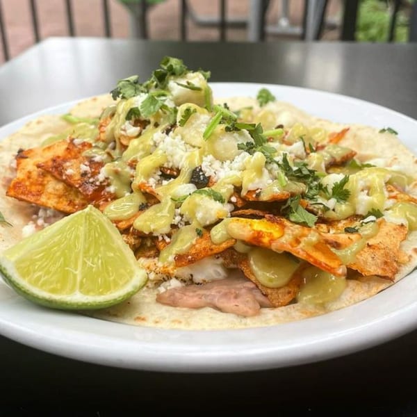 A DGT Tacos Fort Collins taco with chicken, green sauce, cheese, cilantro, and a lime wedge.